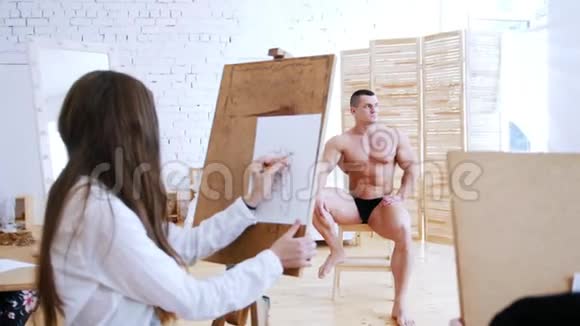女孩在帆布上画了一个肌肉发达的赤膊男焦点人物视频的预览图
