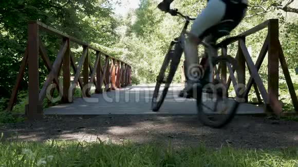 一个人骑着自行车沿着公园里的一座桥行驶在夏天视频的预览图