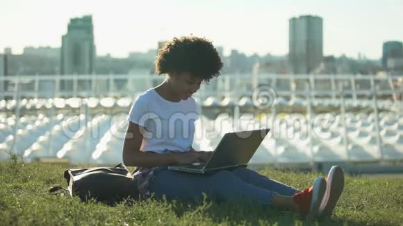漂亮的非裔美国女学生在户外的笔记本电脑上打字自由职业视频的预览图