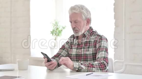严肃的休闲老人在智能手机上讲话视频的预览图