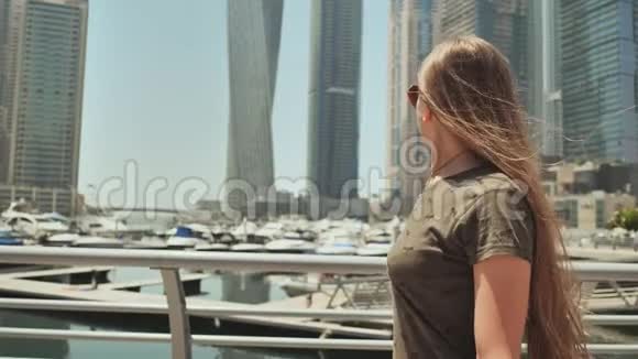 一位留着长发心情愉快的年轻女孩在迪拜码头的海边摆姿势视频的预览图