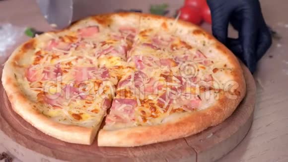 厨师在桌子上的木板上用培根和奶酪切披萨特写侧视视频的预览图