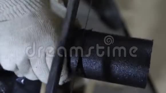 身穿白色防护手套的钳工用钢锯锯黑色管子在车库工作的人特写视频的预览图