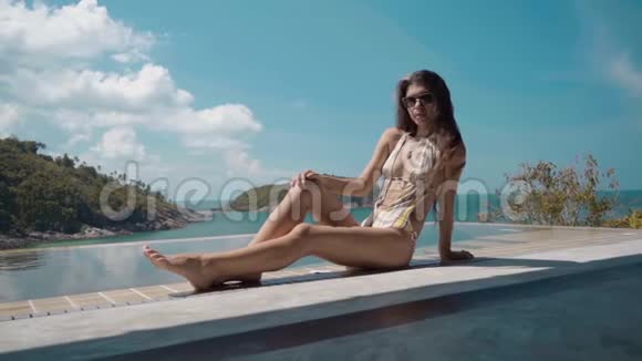 在豪华别墅游泳池边上休息的美女的多利镜头视频的预览图