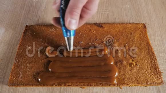 糖果厨师正把糕点袋中的焦糖馅放在海绵蛋糕上视频的预览图