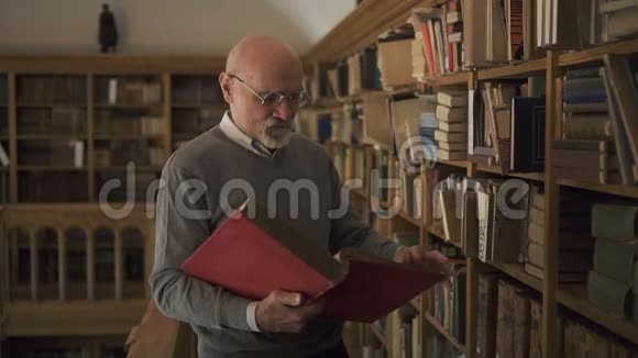 成熟的教授正站在古董图书馆看书视频的预览图