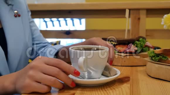女孩用红色指甲的手把糖棒插在中间然后把糖倒进一杯咖啡里视频的预览图