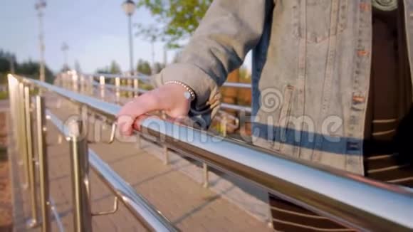 女孩走在闪亮的栏杆上用你的手抓住扶手天气晴朗特写的女手视频的预览图