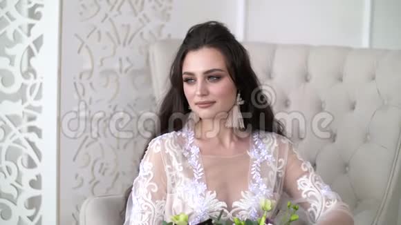 漂亮迷人的女孩坐在椅子上穿白色蕾丝连衣裙的年轻女人视频的预览图