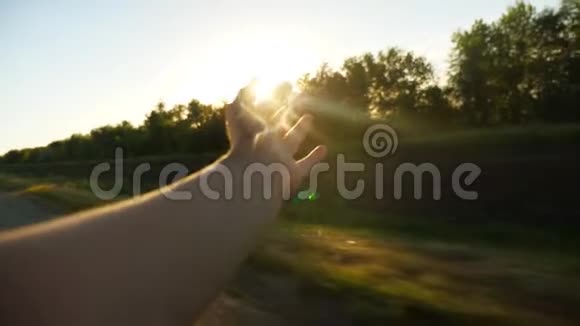 一个女人在夕阳下从车窗里挥手慢动作视频的预览图