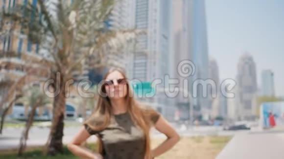 戴太阳镜的女孩在迪拜的街道和棕榈树的背景上面的特写碰撞时的运动射击视频的预览图