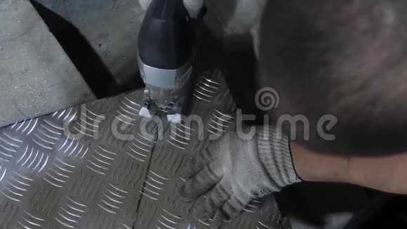 戴防护眼镜的工人用白色防护手套中的电锯锯出一块闪亮的铁皮来自视频的预览图