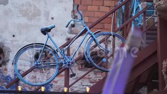 蓝色油漆覆盖的老式自行车挂在附近砖墙上的棕色扶手上视频的预览图
