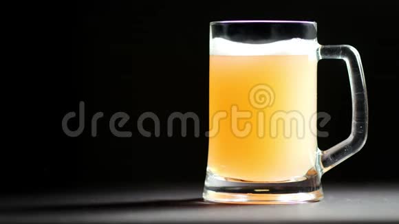 大杯啤酒与泡沫慢慢旋转隔离在黑色工作室背景视频的预览图