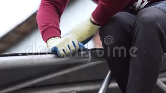 工人用白色塑料销将灰色防水布固定在铝结构上视频的预览图