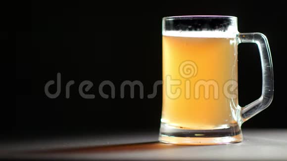 大杯满是茶点金色啤酒饮料慢慢旋转隔离在黑色工作室背景视频的预览图