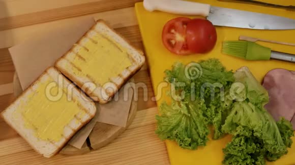 在厨房里做三明治从上面看一只手拿着一片绿叶生菜放在白色的烤面包上用y传播视频的预览图