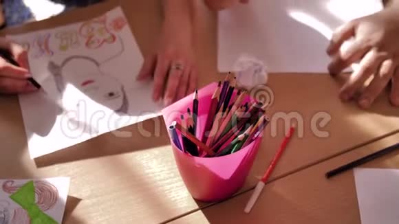 几个人从桌子上的一个红色的展台上拆开彩色铅笔大量的手伸向铅笔视频的预览图