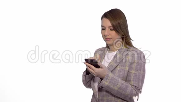 惊讶的金发女孩站在白色背景下一边用手机发短信视频的预览图