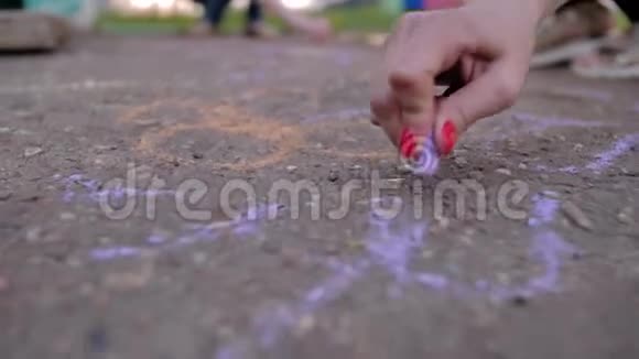 女孩用彩色粉笔在沥青上画画用粉笔特写双手好心情娱乐和休息视频的预览图