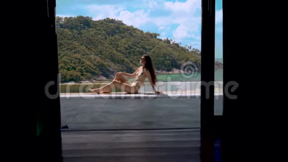 在豪华别墅游泳池边上休息的美女的多利镜头视频的预览图