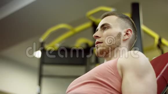大胡子运动员举起哑铃在健身房的长凳上做二头肌特写镜头视频的预览图