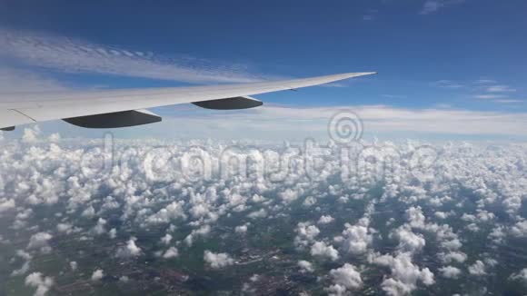 飞机在蓝天上飞行白云和城市下面的飞机翼下视频的预览图