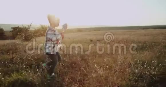 跑步的小男孩看起来很可爱带着一根大棒棒糖穿过田野阳光令人惊叹视频的预览图