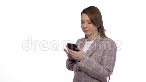 惊讶的金发女孩站在白色背景下一边用手机发短信视频的预览图