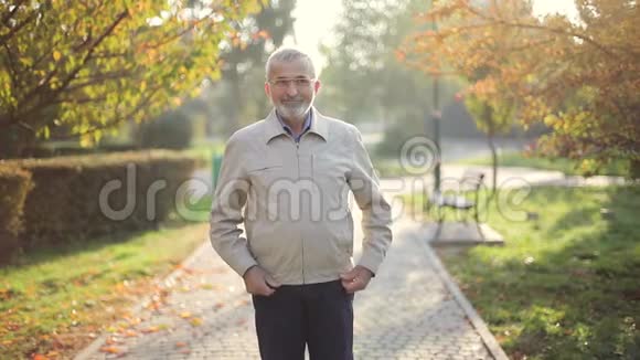 穿夹克的老人秋天公园散步的老胡子视频的预览图
