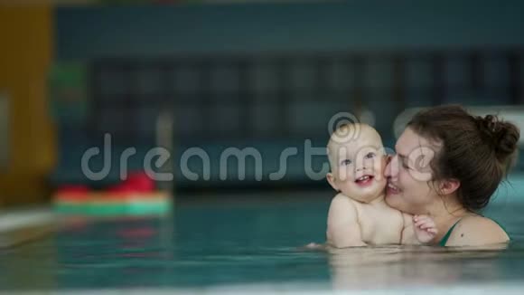 一岁的孩子和妈妈一起在游泳池里游泳这孩子正热情地在水里划手视频的预览图