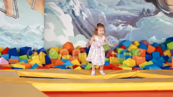 小女孩跳在蹦床上在孩子们操场上玩耍儿童游戏视频的预览图