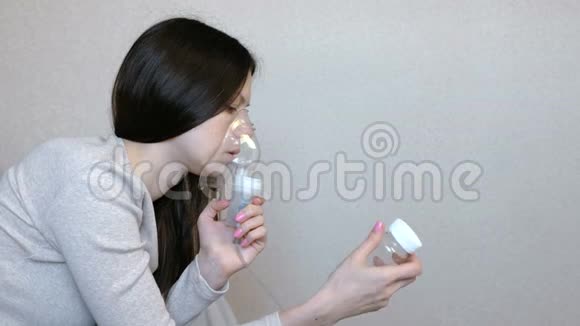 使用雾化器和吸入器进行治疗年轻女性通过吸入面罩吸入侧视在一个视频的预览图