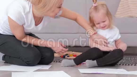 小可爱的金发女孩画黑色毛笔妈妈坐在沙发附近视频的预览图