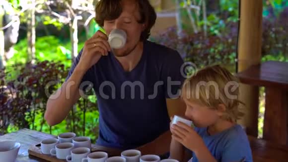 父亲和儿子在一家热带咖啡馆里品茶视频的预览图