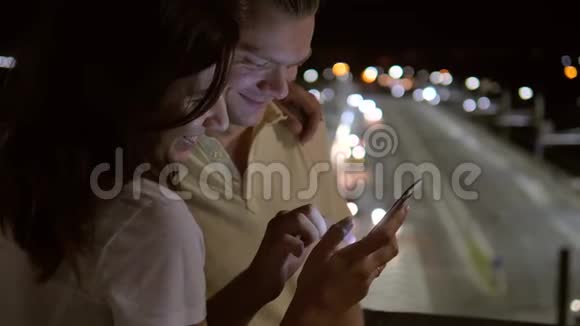 幸福的一对夫妇在街上微笑一起看着智能手机视频的预览图