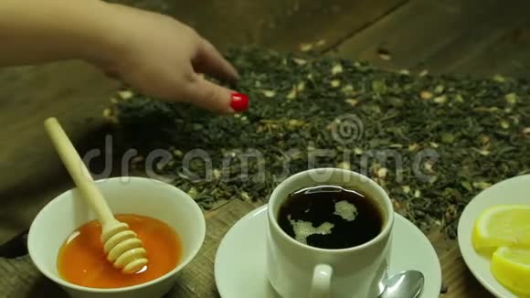 女人的手把茶写在散落在木桌上的茶叶上视频的预览图