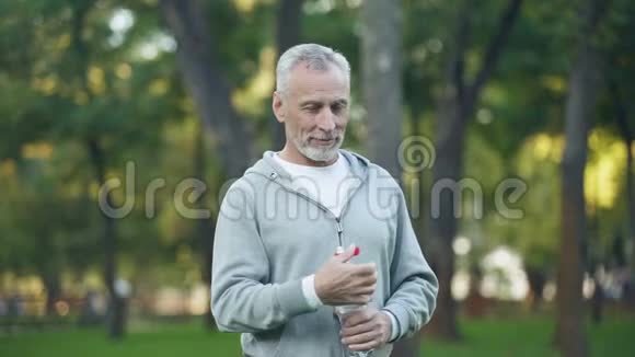 在公园锻炼保健体育运动后活跃的祖父饮用水视频的预览图