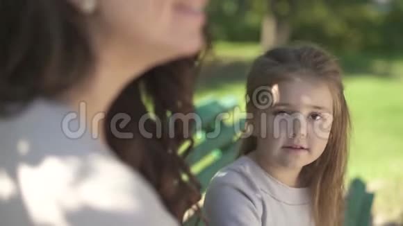 妈妈和她的小女儿正在公园的长凳上休息视频的预览图