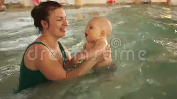 妈妈教她的孩子在一个封闭的公共游泳池里游泳孩子正在水上公园的人工海浪上摇摆视频的预览图