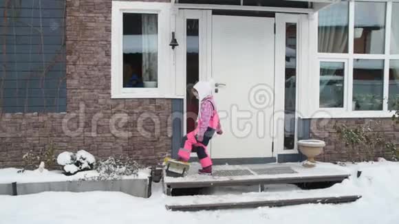 女孩一个孩子在雪地里擦鞋然后进屋视频的预览图