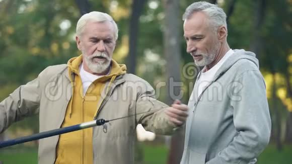 老年男性向朋友展示新鱼竿养老爱好聚会视频的预览图