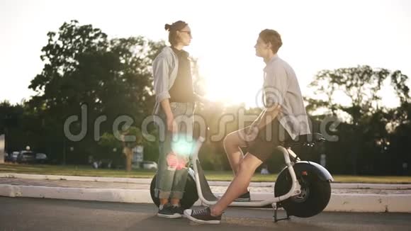 年轻的男性和女性在户外有时间在一起男孩坐在电动迷你自行车上微笑女孩在视频的预览图