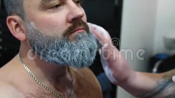 为扮演圣诞老人角色训练的人弗罗斯特神父嬉皮士基的白发胡须化妆师给一个人化妆视频的预览图