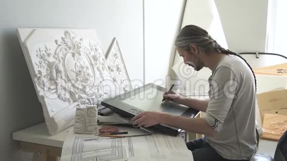 成熟的设计师将白色石膏造型与花卉装饰复制到大的图形平板上视频的预览图