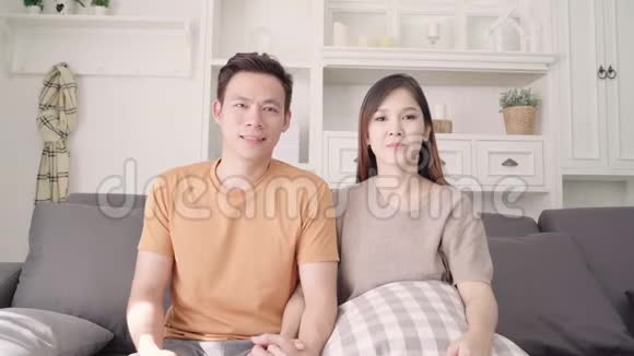 亚洲夫妇在家里的电视客厅前为足球比赛欢呼视频的预览图