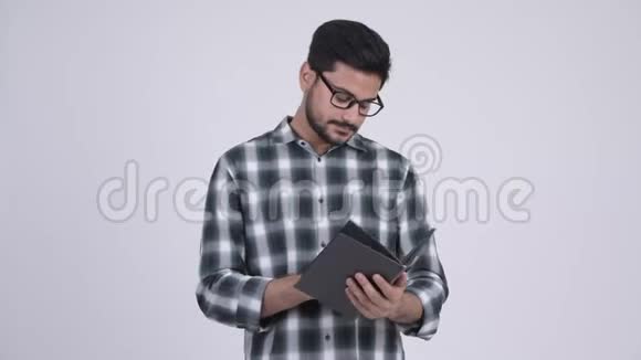 年轻的留胡子的印度男人带着眼镜看书视频的预览图