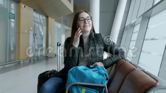 幸福的女人正在用手机聊天等待她在机场的航班视频的预览图