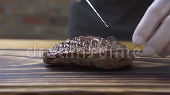 厨师把切肉牛排的手放在肉片上将切好的烤肉放在木板上煮熟加工烹饪食品视频的预览图