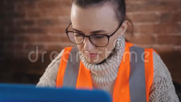 专注的女建筑工人在建筑工地的房间里使用笔记本电脑和技术文档视频的预览图